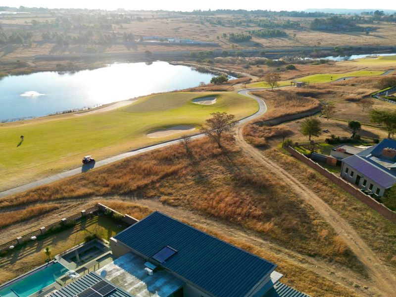 Aerial view of a residential property featuring a swimming pool, solar panels, and direct access to a scenic golf course and lake.