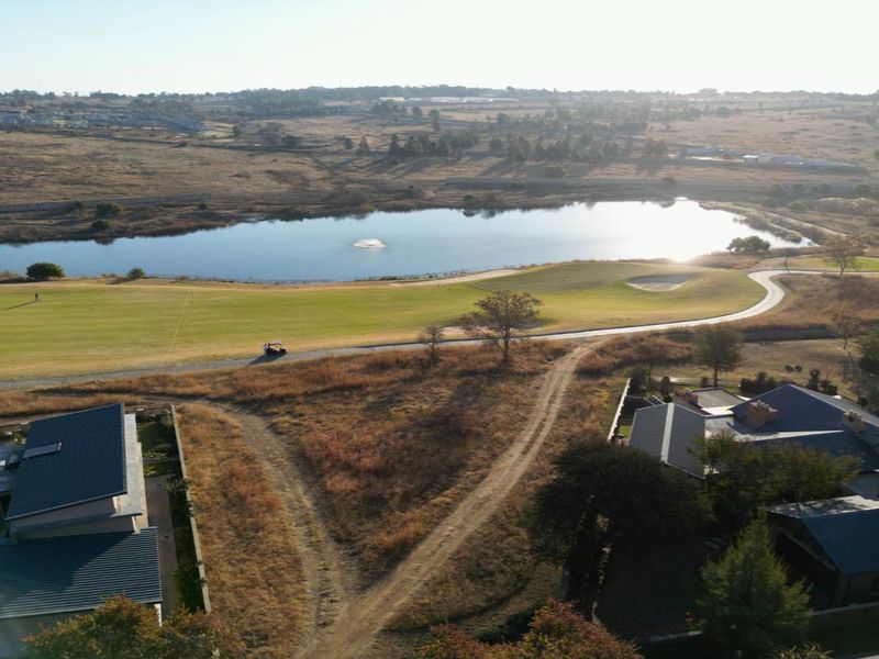 Aerial view of the residential property overlooking a scenic golf course, lake, and surrounding landscape.