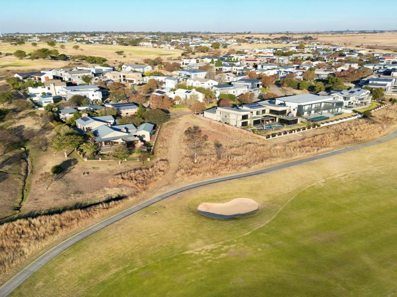 An aerial view of a residential estate situated adjacent to a golf course, showcasing the surrounding landscape and neighborhood layout.