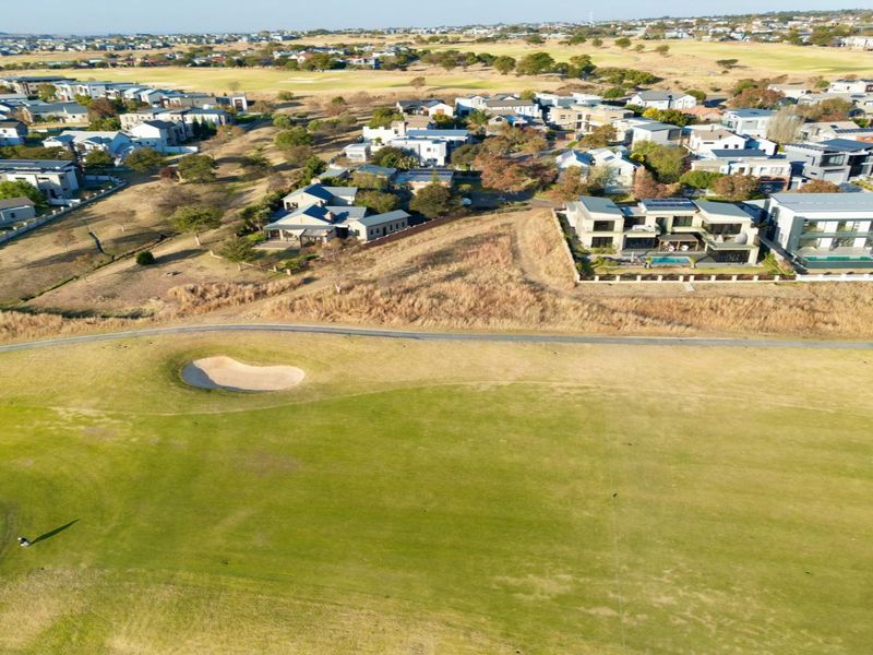 Aerial view of a residential estate bordering a golf course, showcasing the surrounding landscape and neighborhood layout.
