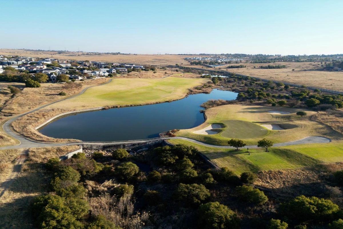 An aerial view of a residential golf estate featuring a large lake, manicured greens, and surrounding natural landscape.