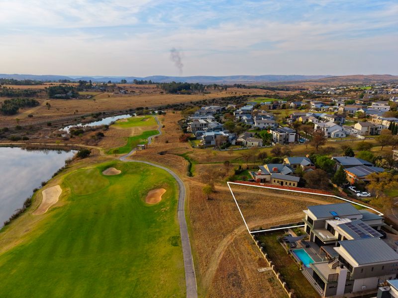 Aerial view of a residential property plot situated adjacent to a golf course and lake, showcasing the surrounding estate landscape.
