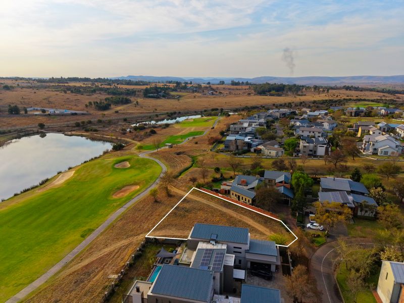 Aerial view of a vacant residential plot situated within a golf estate, featuring scenic views of the course and surrounding landscape.
