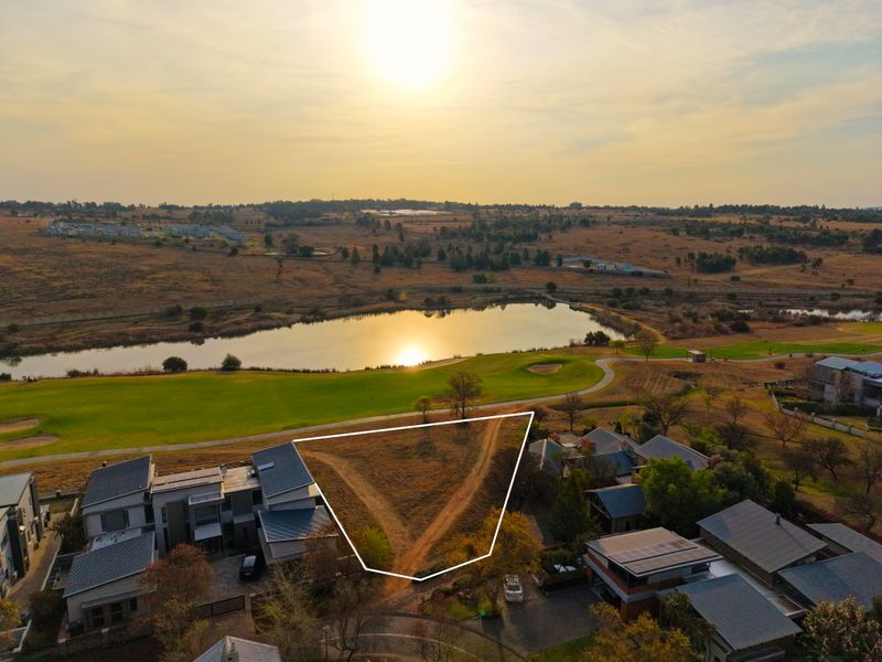 An aerial view of a vacant residential plot situated in a prime location overlooking a golf course and lake.