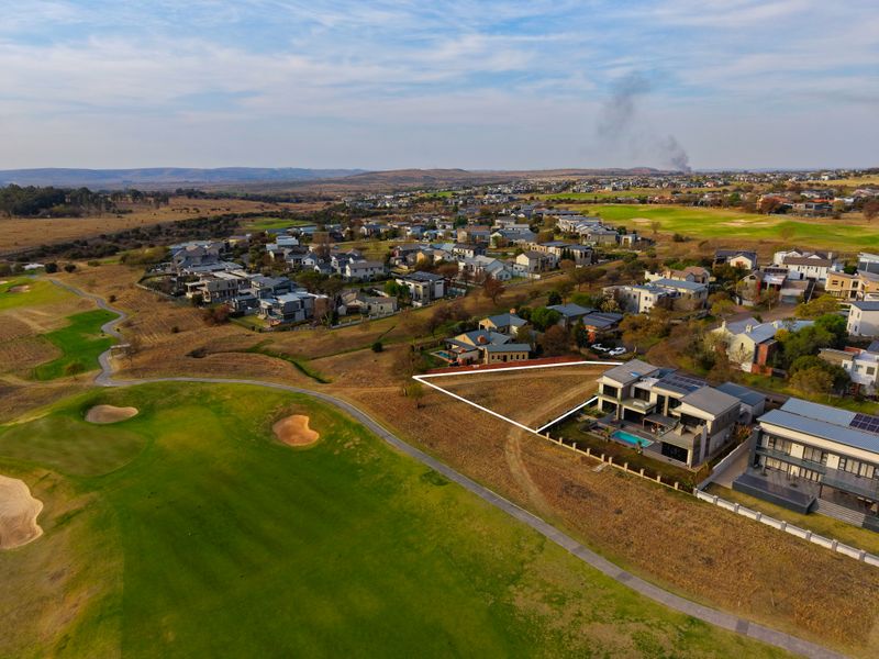 Aerial view of a vacant residential plot situated directly adjacent to a golf course in a developed estate.