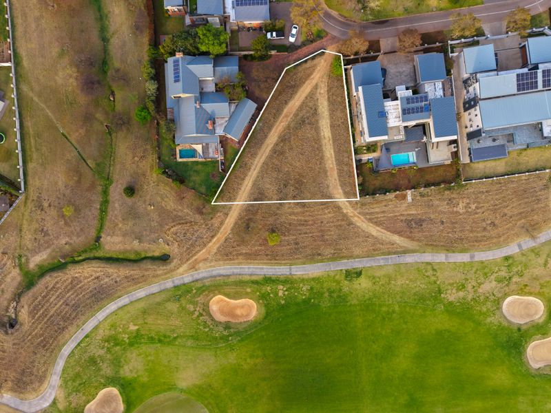 An aerial view of a vacant residential plot situated adjacent to a golf course, highlighting the property boundaries and surrounding neighborhood context.