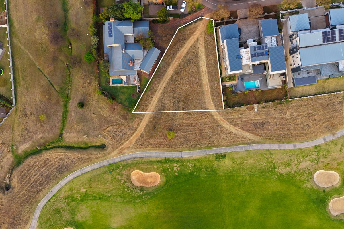 An aerial view of a vacant residential plot situated adjacent to a golf course, highlighting the property boundaries and surrounding neighborhood context.
