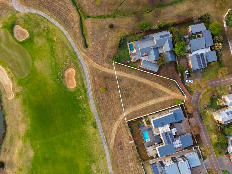 Aerial view of a vacant residential land plot situated adjacent to a golf course, offering a prime location for development.