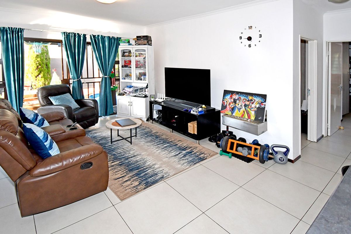A spacious living room featuring large format floor tiles and sliding glass doors providing direct access to the outdoor patio area.