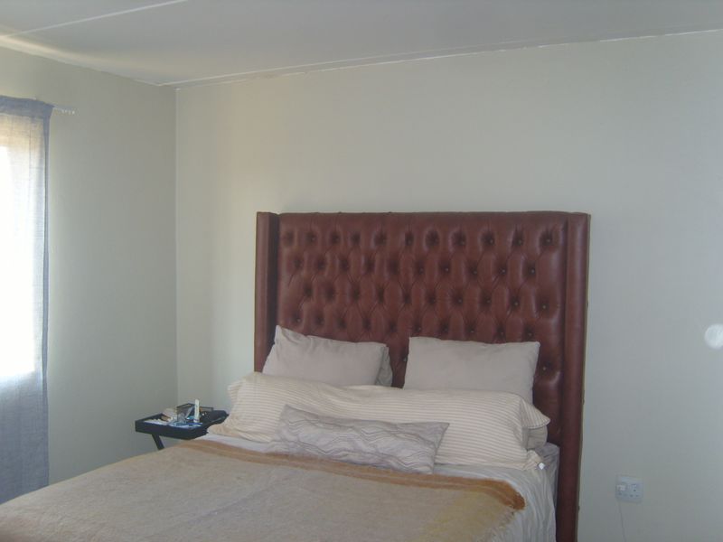 A simple bedroom featuring neutral wall finishes and a single electrical outlet.