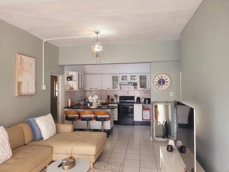 Open-plan living area featuring a functional kitchen with black granite countertops, breakfast bar, and tiled flooring throughout the combined space.