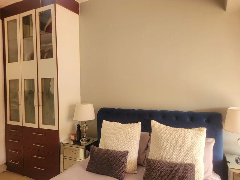 A bedroom featuring a large, dark wood built-in wardrobe with glass-paneled doors and integrated storage drawers.