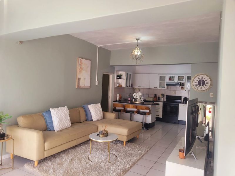 Open-plan living area featuring a functional kitchen with built-in cabinetry, breakfast counter, and tiled flooring throughout the combined space.