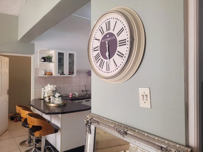 A view of a kitchen area featuring a breakfast bar, tiled backsplash, and built-in cabinetry, viewed from an adjacent living space.