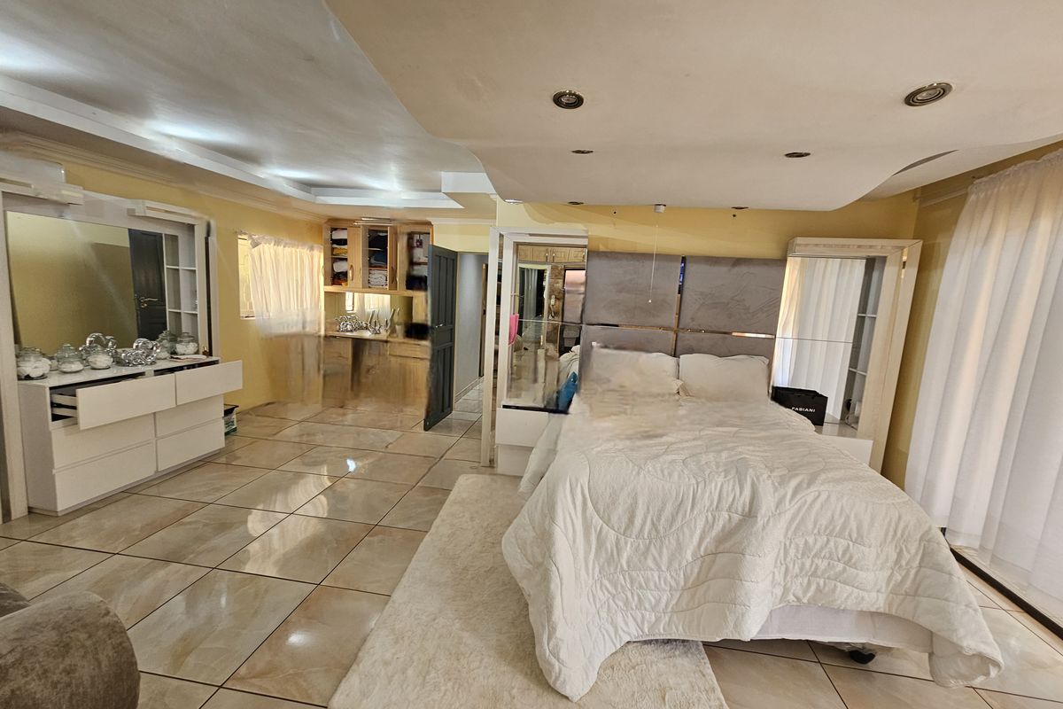 Spacious bedroom featuring tiled flooring, recessed ceiling lighting, and integrated built-in cabinetry with mirrored wardrobe panels.