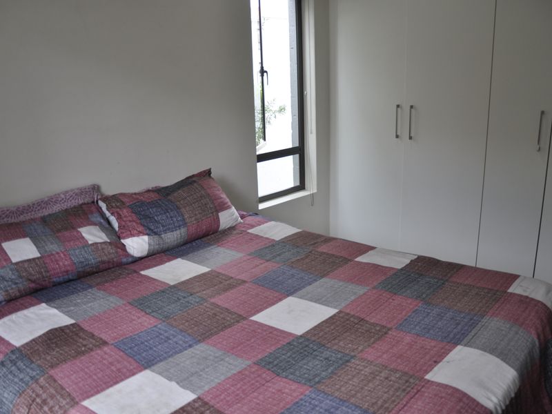 A functional bedroom featuring a built-in wardrobe and a window providing natural light.