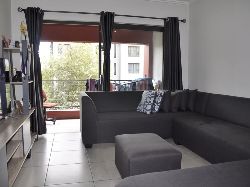 A living room featuring tiled flooring and a large sliding glass door providing access to an outdoor balcony area.