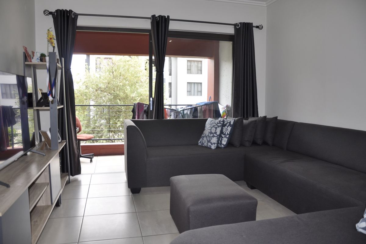 A living room featuring tiled flooring and a large sliding glass door providing access to an outdoor balcony area.
