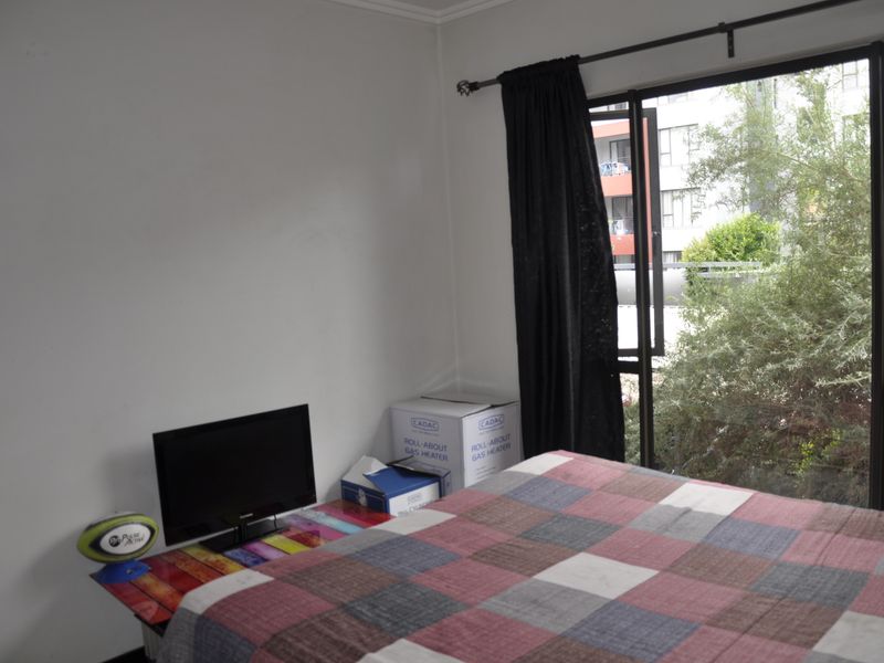 A bedroom featuring a large sliding glass door that provides natural light and views of the surrounding apartment complex.