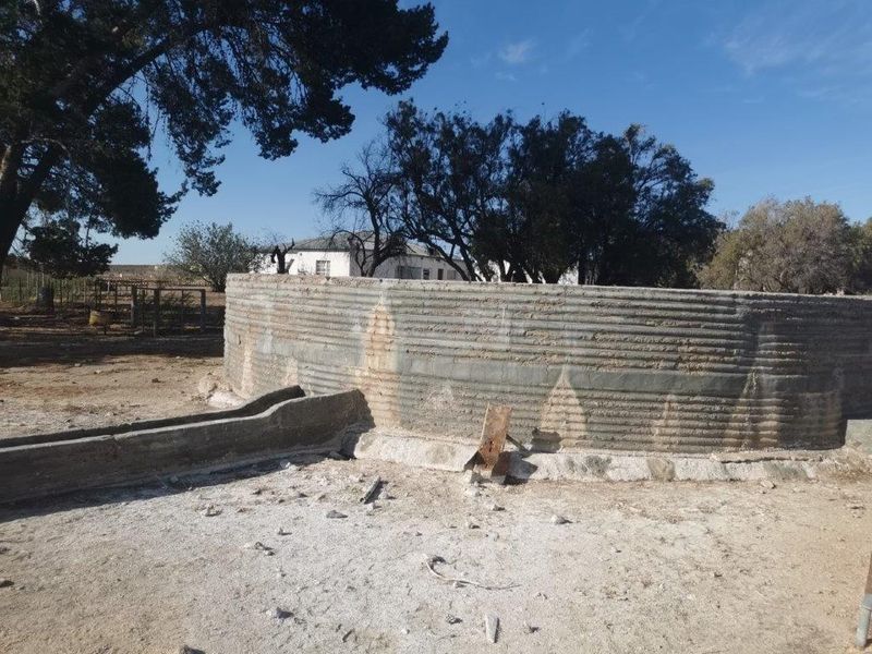 A weathered concrete water reservoir and attached livestock trough located on the farm property.