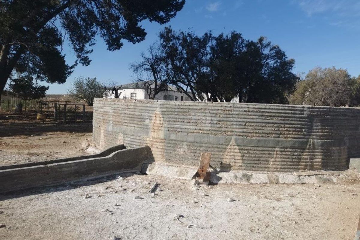 A weathered concrete water reservoir and attached livestock trough located on the farm property.