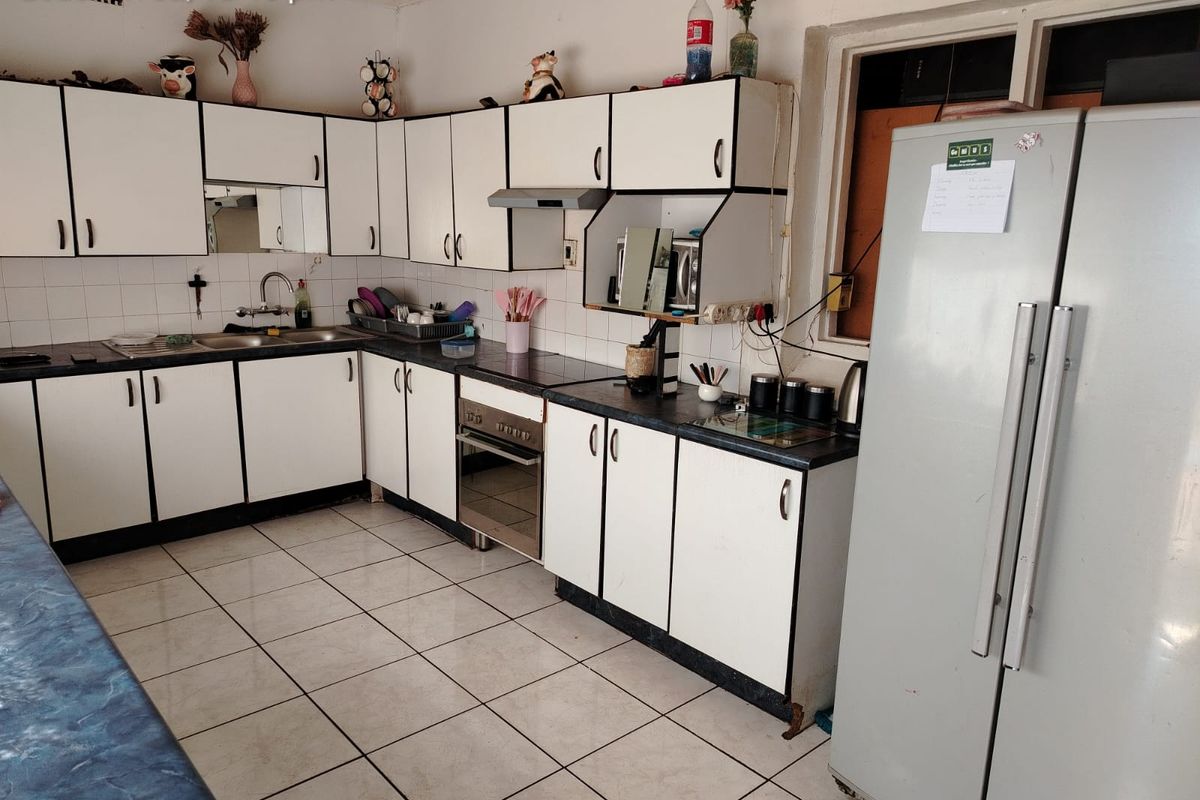 A functional kitchen featuring white built-in cabinetry, laminate countertops, a built-in oven with extractor fan, and tiled flooring throughout.