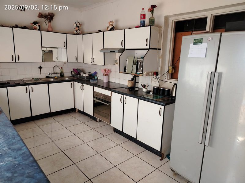 A functional kitchen featuring white built-in cabinetry, laminate countertops, a built-in oven with extractor fan, and tiled flooring throughout.