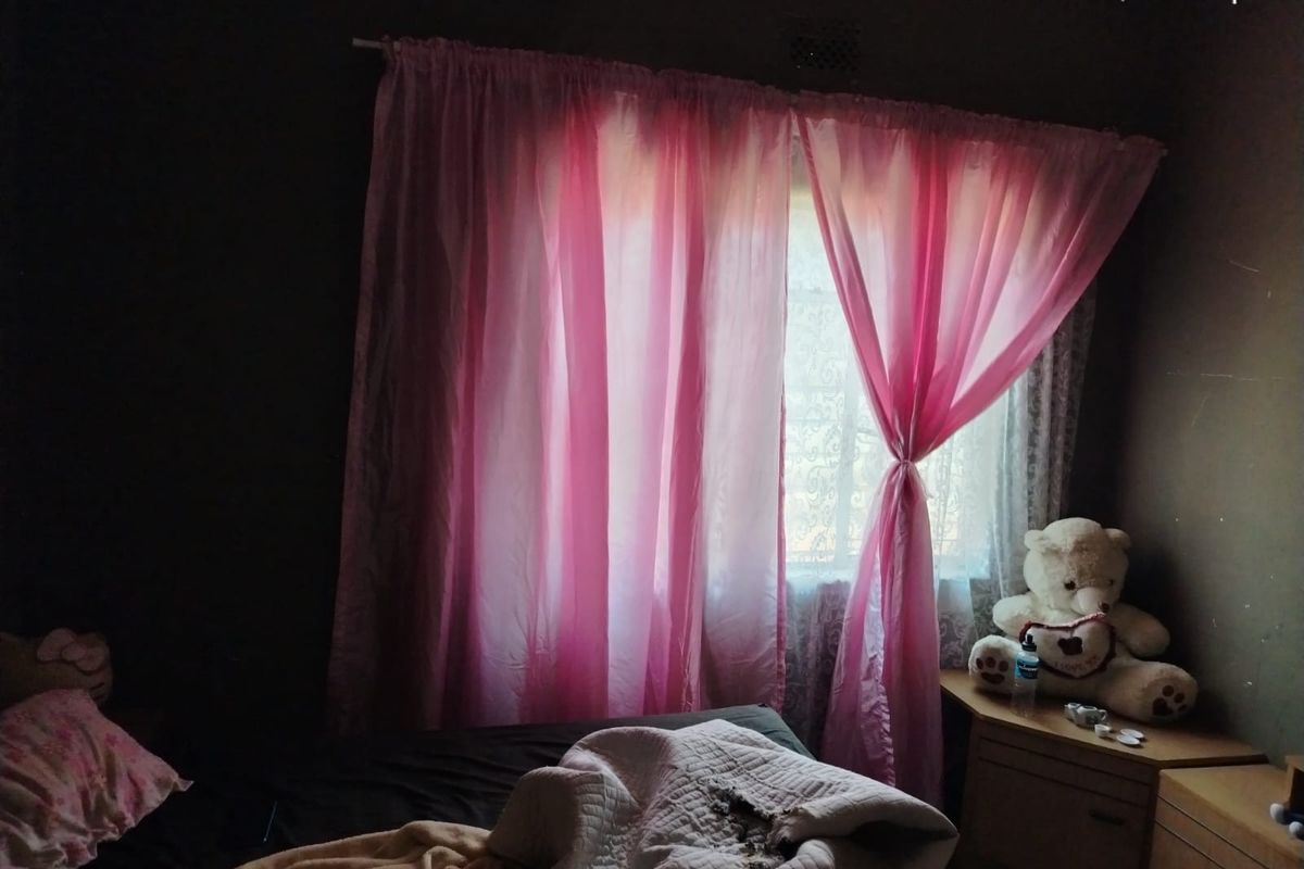 A bedroom featuring a window with pink curtains, providing natural light to the space.
