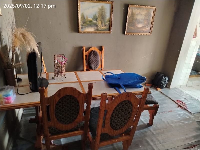 A dining area featuring a tiled table and dated wall finishes, requiring cosmetic updates to improve the overall aesthetic and condition of the space.