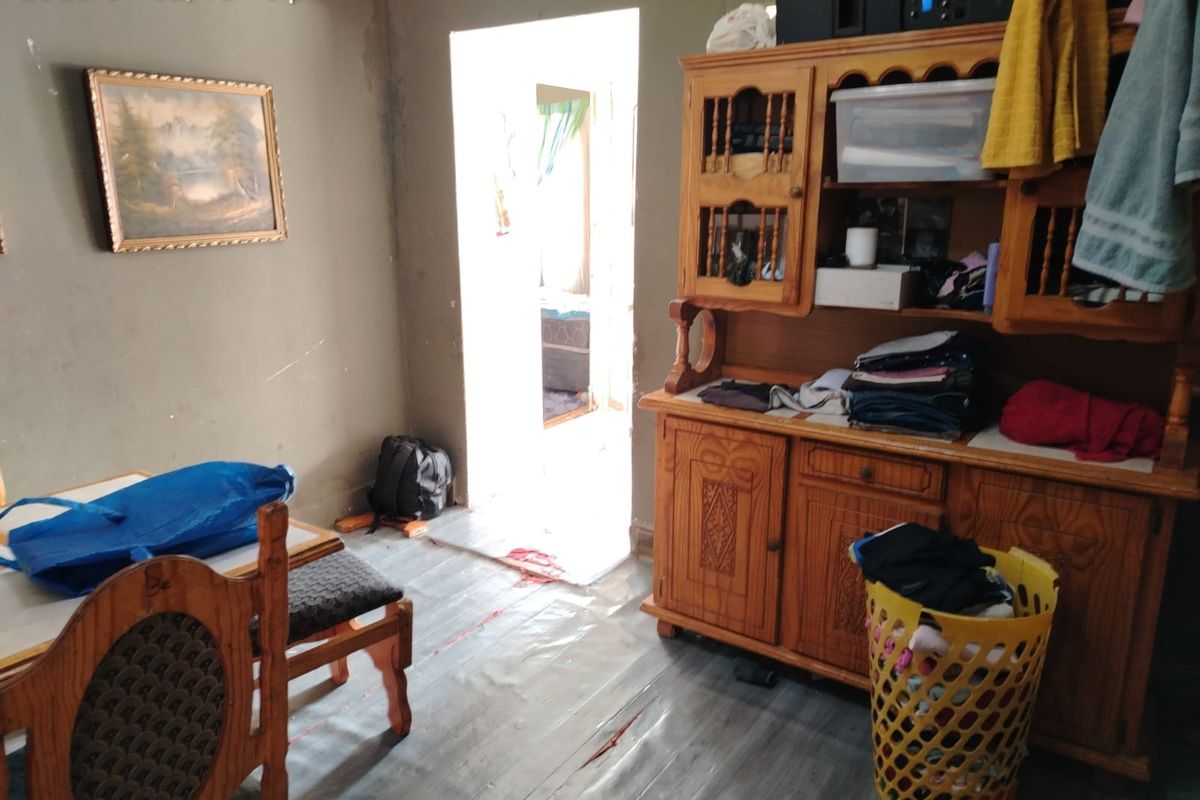 A living area featuring worn flooring and unfinished wall surfaces, requiring cosmetic updates and repairs to improve the overall condition of the space.