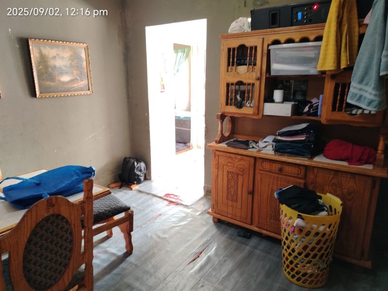 A living area featuring worn flooring and unfinished wall surfaces, requiring cosmetic updates and repairs to improve the overall condition of the space.