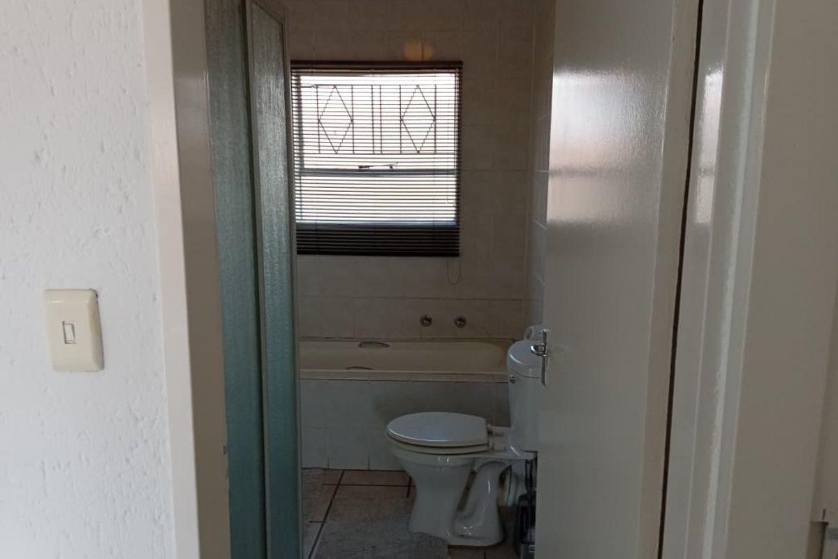 A functional bathroom featuring a built-in bathtub, toilet, and tiled walls, offering a practical layout for an apartment setting.