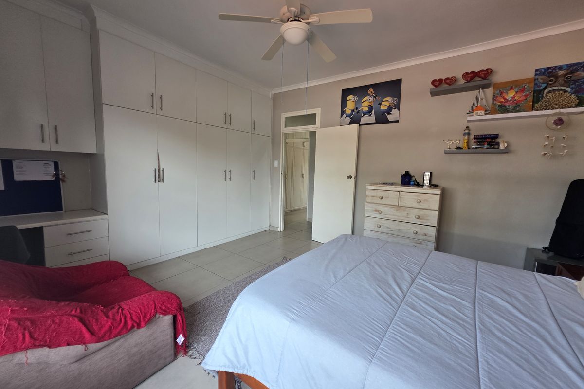 A well-lit bedroom featuring extensive built-in cabinetry, a built-in desk, and neutral tiled flooring, offering ample storage and functional living space.