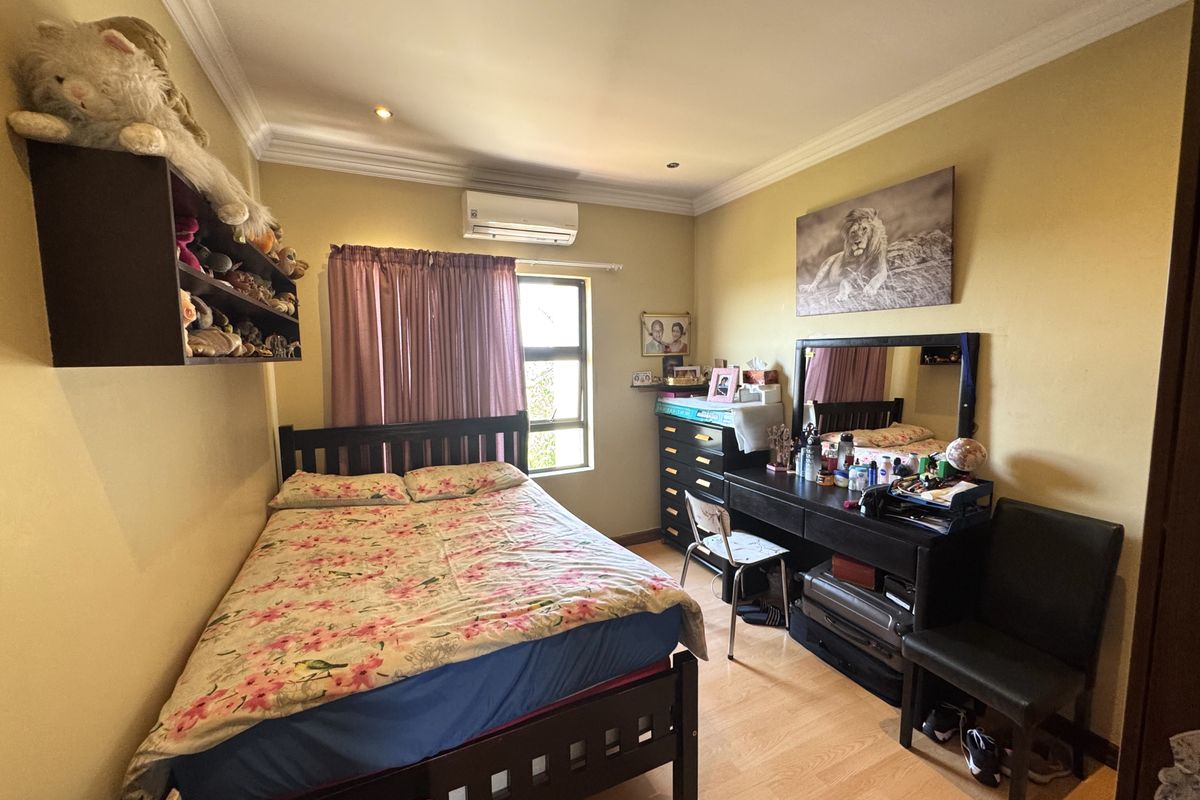 A functional bedroom featuring laminate flooring, crown molding, and a wall-mounted air conditioning unit.