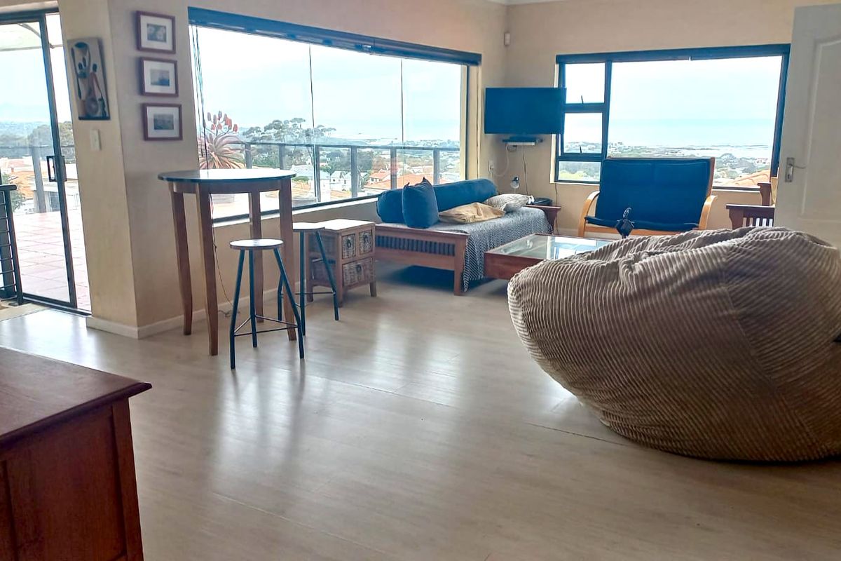 Spacious living area featuring large windows with expansive views, laminate flooring, and direct access to an outdoor patio through a sliding glass door.