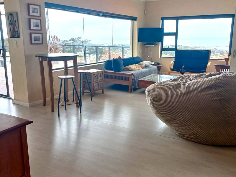 Spacious living area featuring large windows with expansive views, laminate flooring, and direct access to an outdoor patio through a sliding glass door.