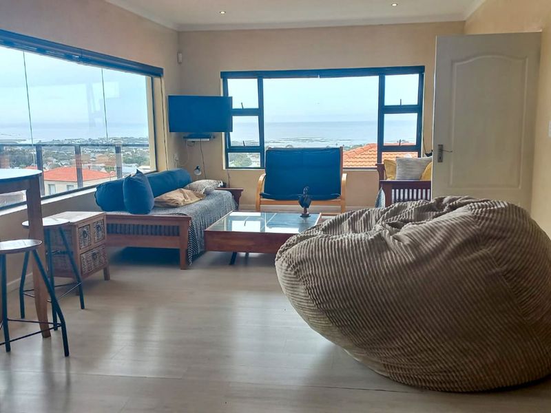 Spacious living room featuring large windows with expansive coastal views, recessed ceiling lighting, and light-toned laminate flooring.