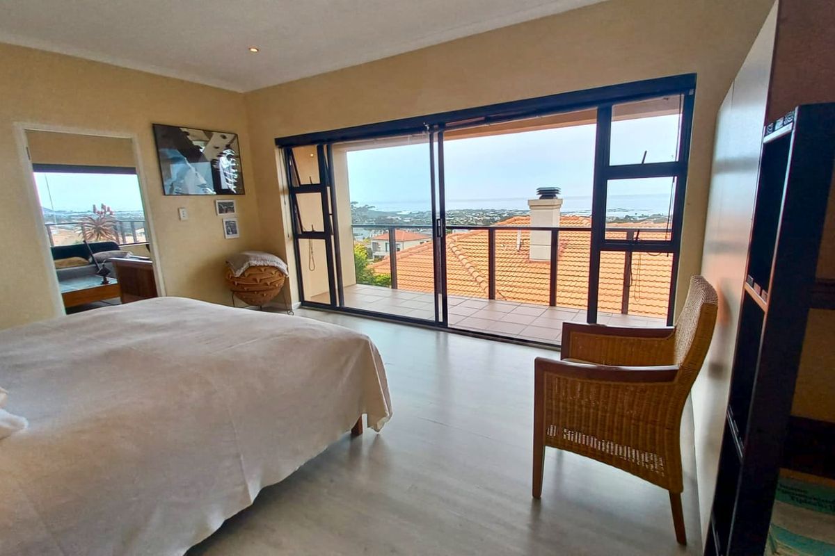 Spacious bedroom featuring large sliding glass doors that open onto a private balcony with scenic coastal views.