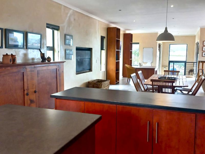 Spacious open-plan living and kitchen area featuring built-in cabinetry, a central kitchen island, and a fireplace, offering a versatile layout for modern living.