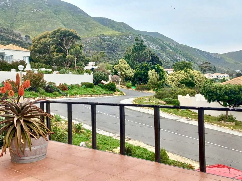 An elevated balcony featuring tiled flooring and a metal railing, offering scenic views of the surrounding neighborhood and mountain landscape.