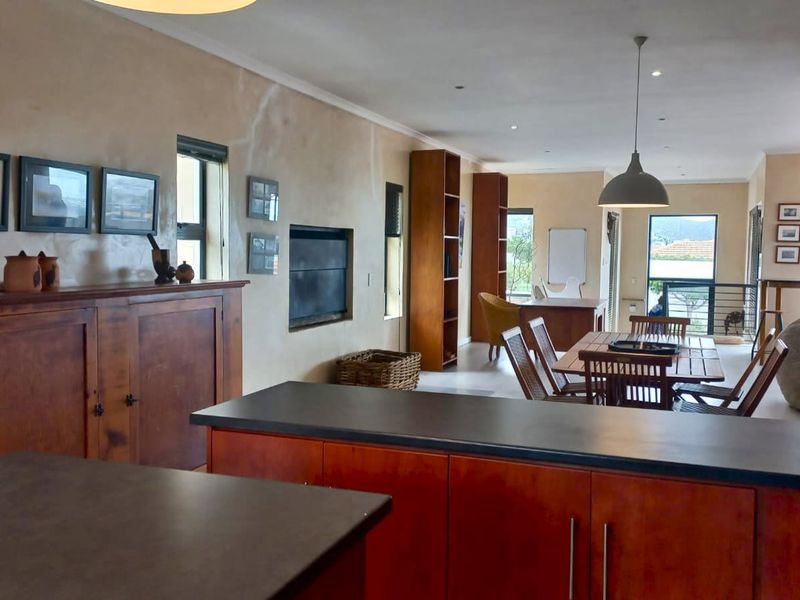 Spacious open-plan living and kitchen area featuring built-in cabinetry, stone countertops, and a fireplace, offering a versatile layout for dining and relaxation.