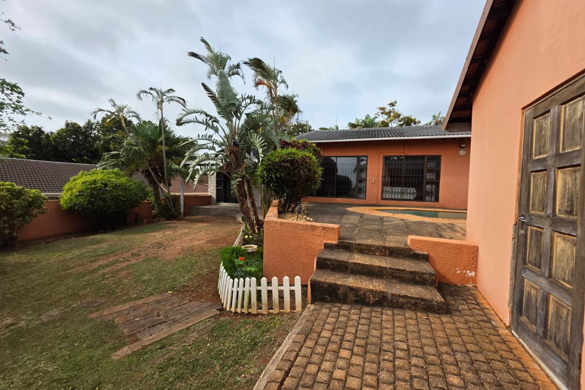 Rear exterior view featuring a paved patio area, concrete steps, and a swimming pool set against the house facade.