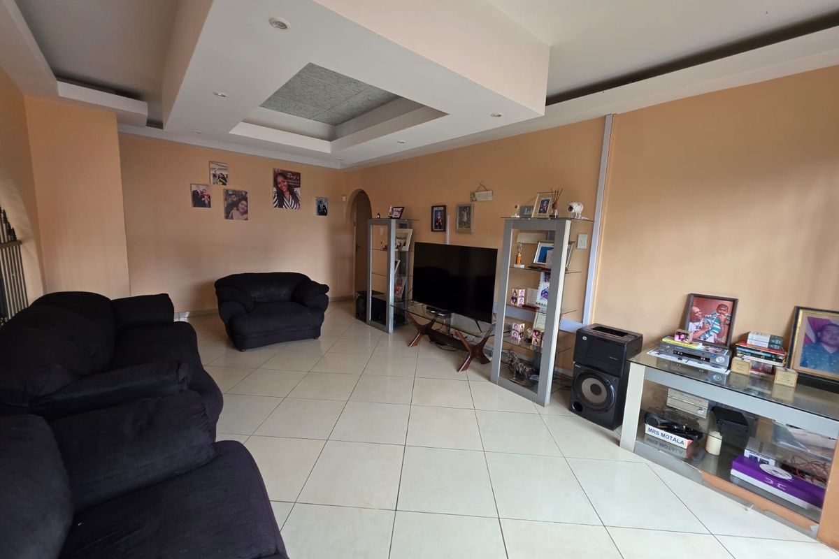 Spacious living room featuring a recessed ceiling with downlights and neutral tiled flooring, offering a comfortable and functional layout for family relaxation.