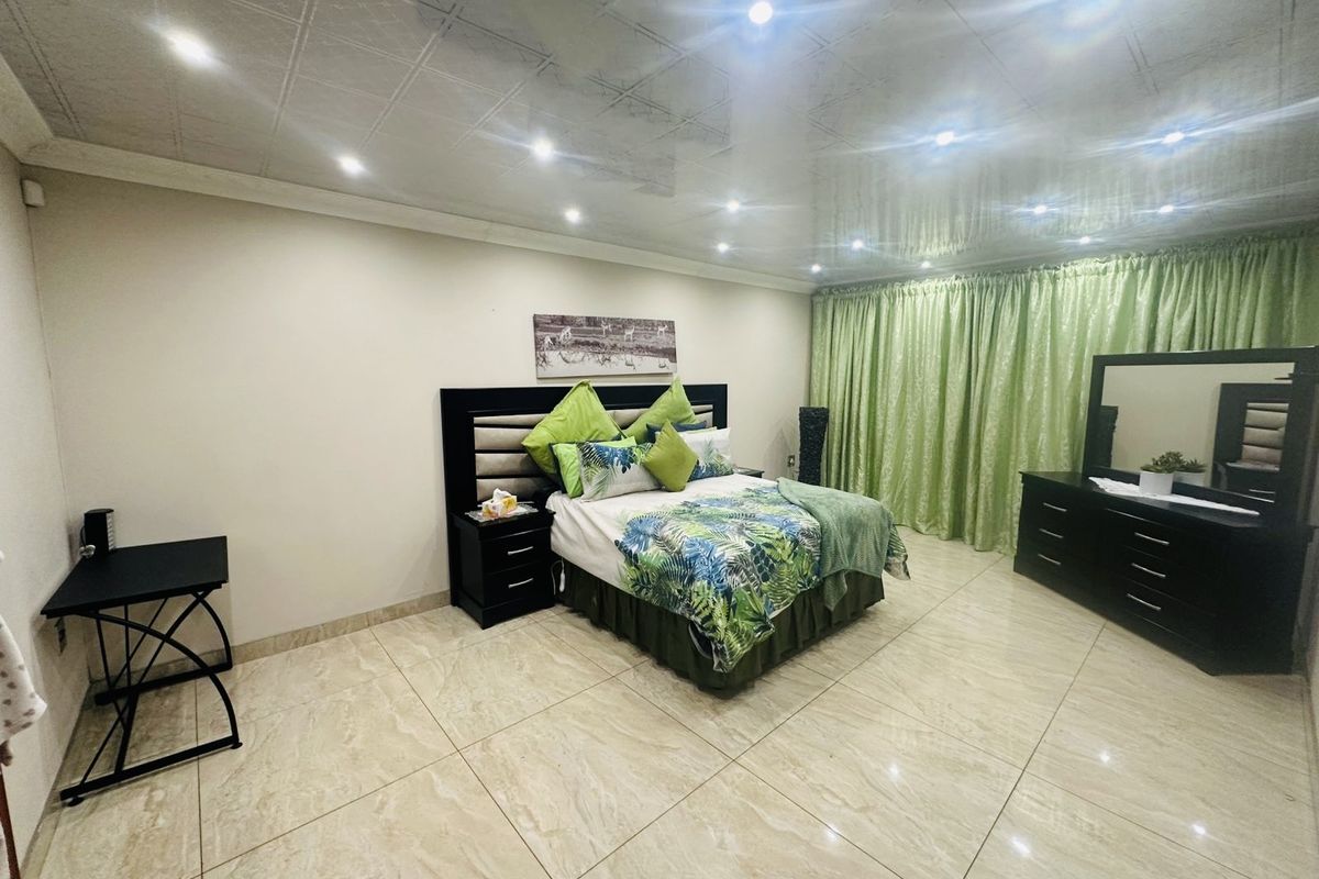 Spacious bedroom featuring large format floor tiles, recessed downlighting, and a glossy ceiling finish, providing a bright and modern foundation for the space.