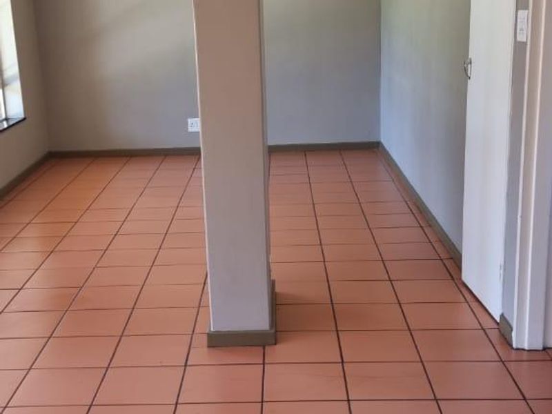 An empty living area featuring terracotta-style ceramic floor tiles and a central structural support column.