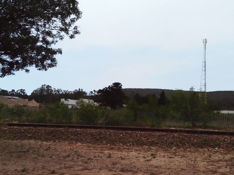 A view of the surrounding landscape featuring railway tracks, perimeter fencing, and a distant telecommunications tower.