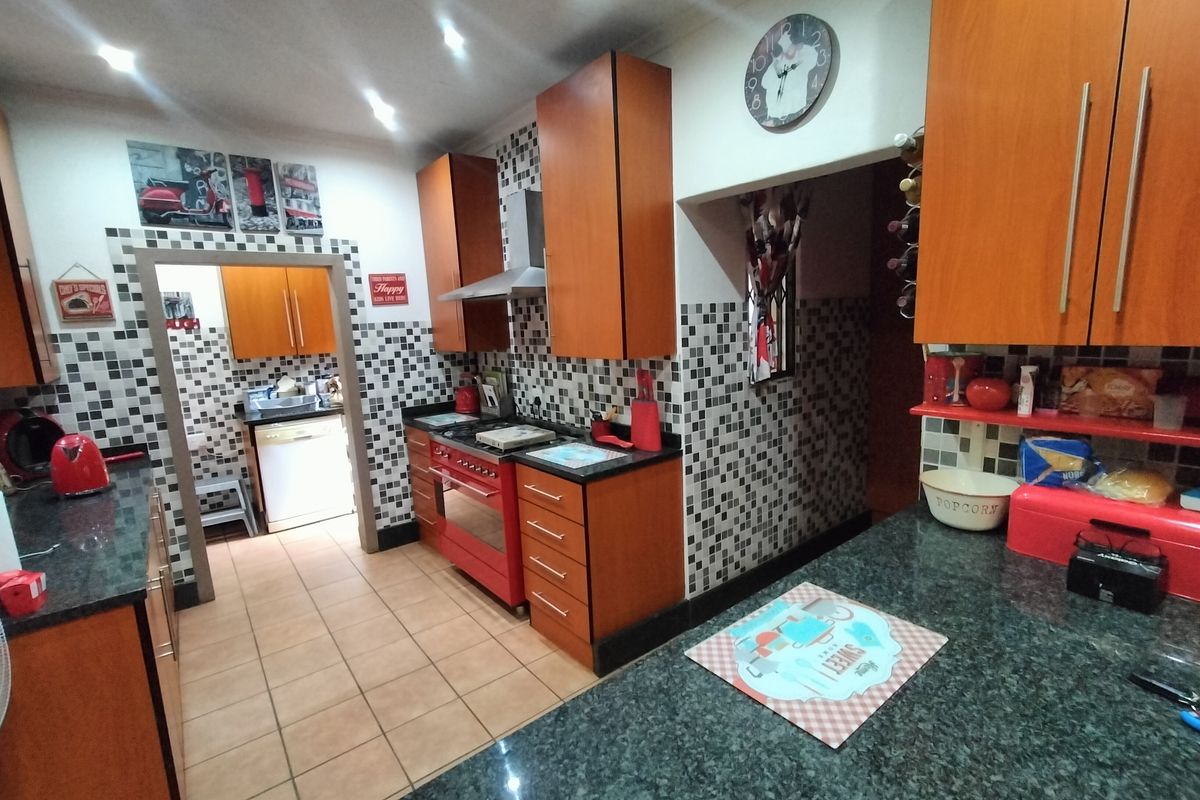 A functional kitchen featuring wood-finish cabinetry, granite countertops, a mosaic tile backsplash, and a built-in oven with an extractor fan.