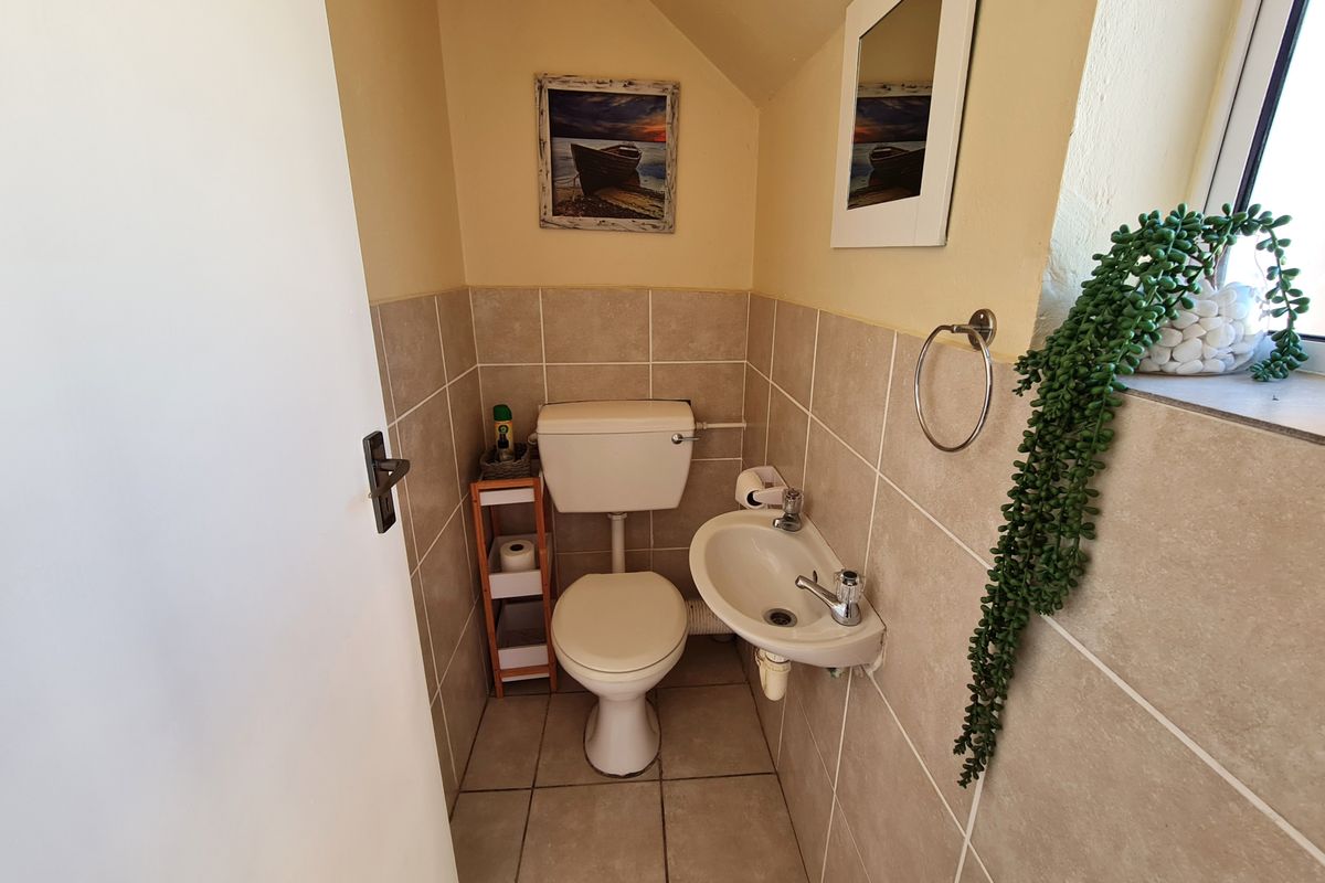 Compact guest bathroom featuring a wall-mounted basin, toilet, and neutral tiled finishes.
