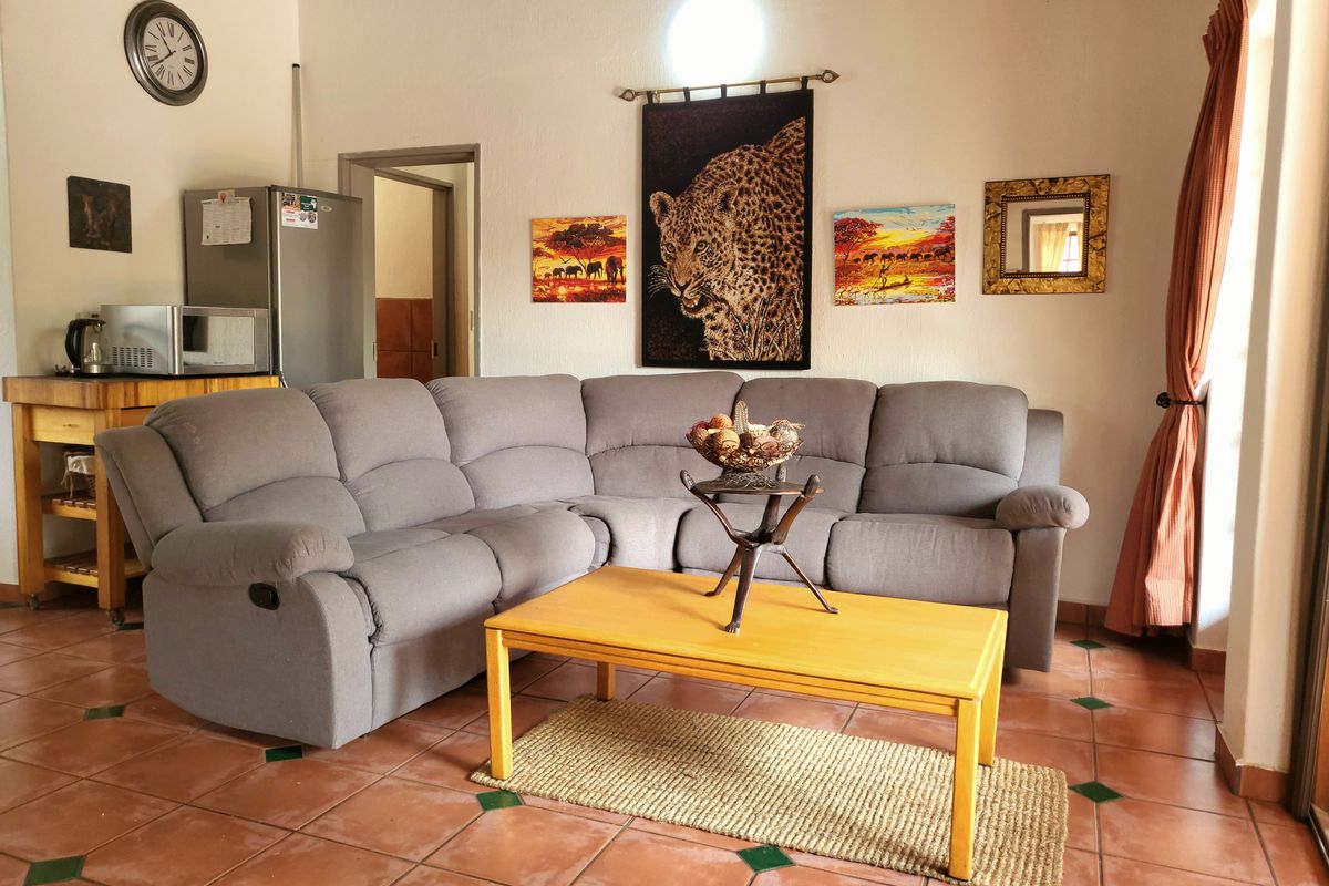 A comfortable living room featuring terracotta floor tiles and a neutral layout, providing a functional space for relaxation.