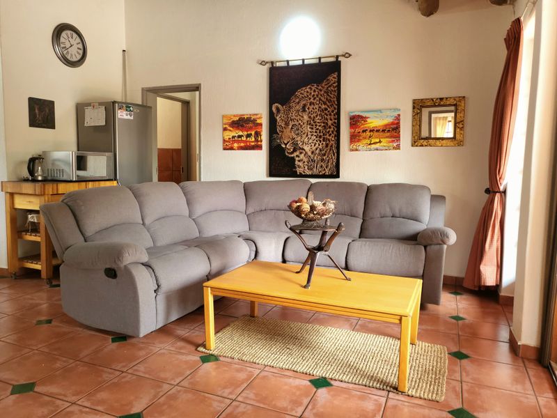 A comfortable living room featuring terracotta floor tiles and a neutral layout, providing a functional space for relaxation.